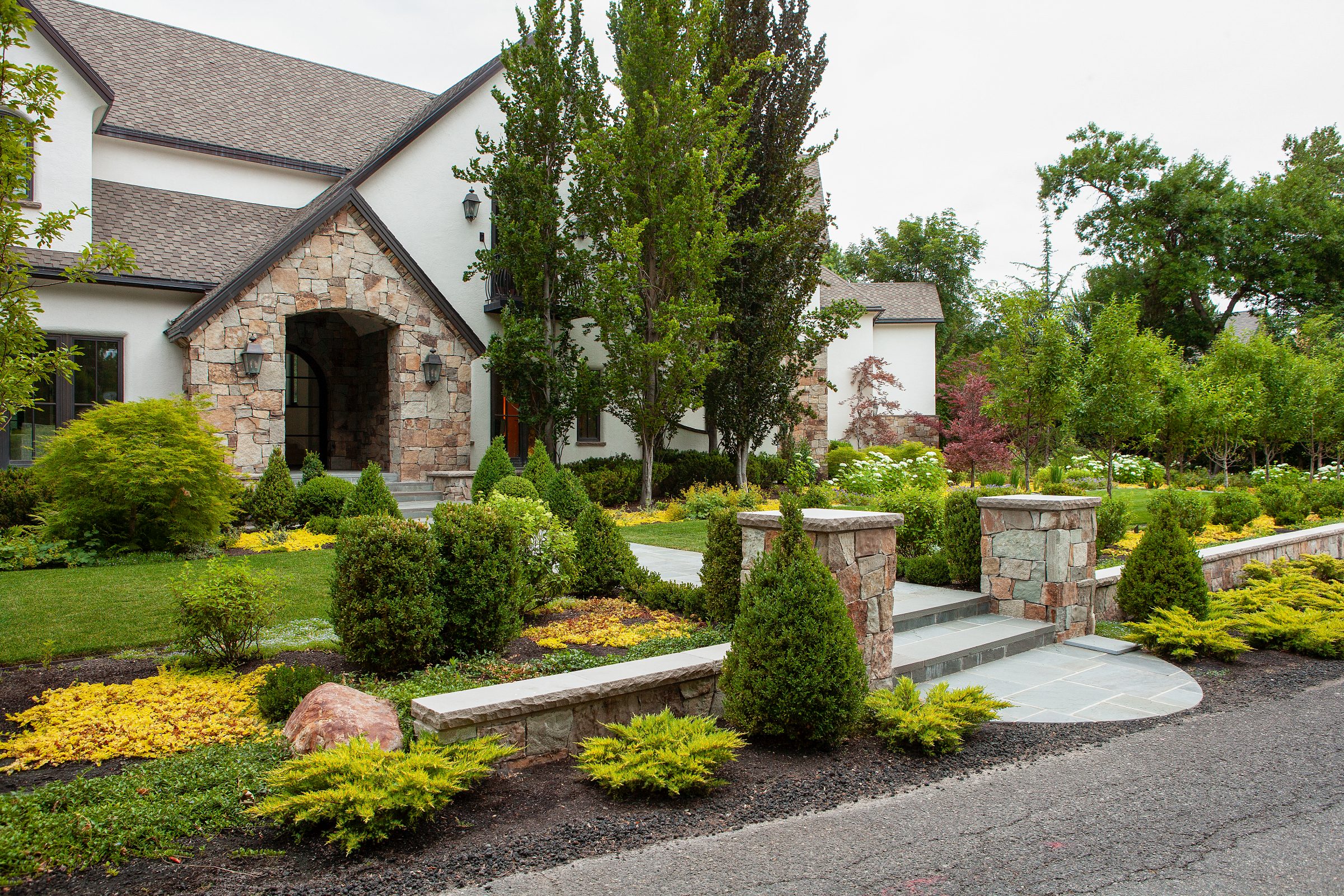 Elegant stone house with lush garden landscape.