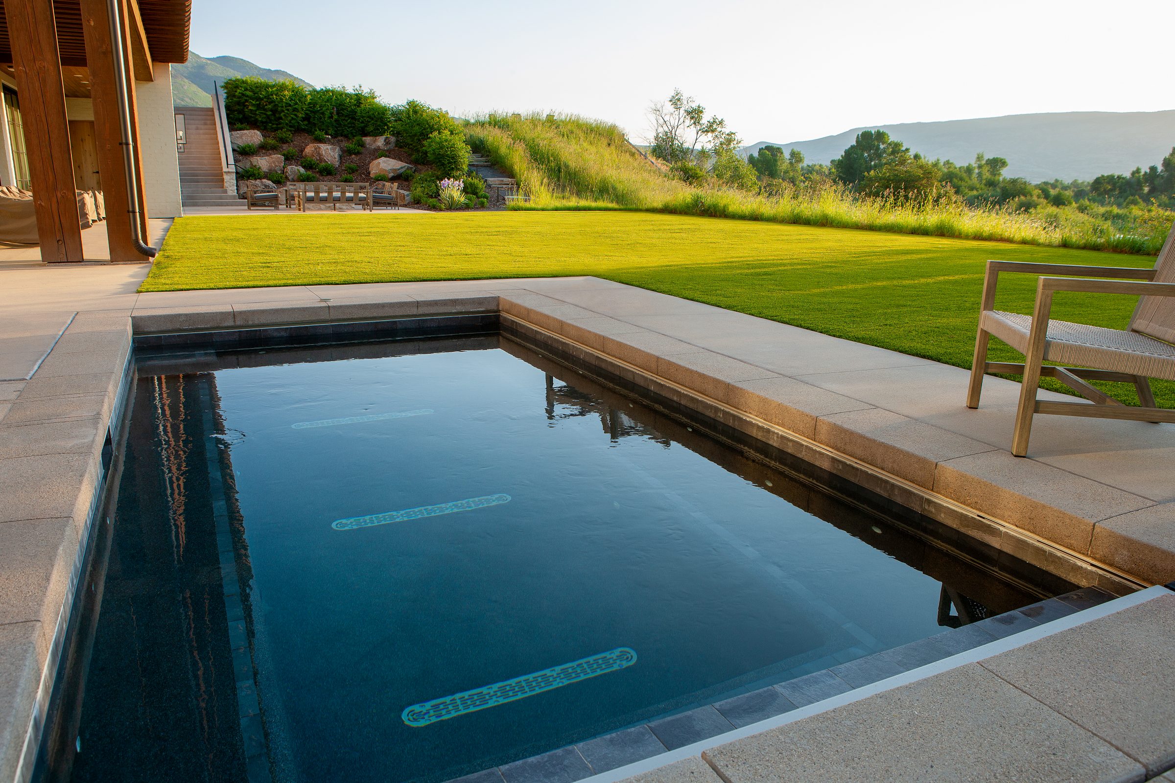 Tranquil backyard pool with mountain view at sunset.
