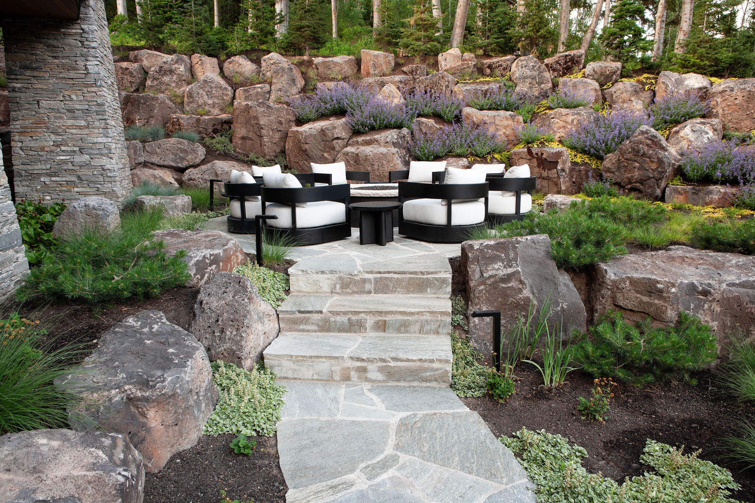 Stone patio with chairs and lush landscaping