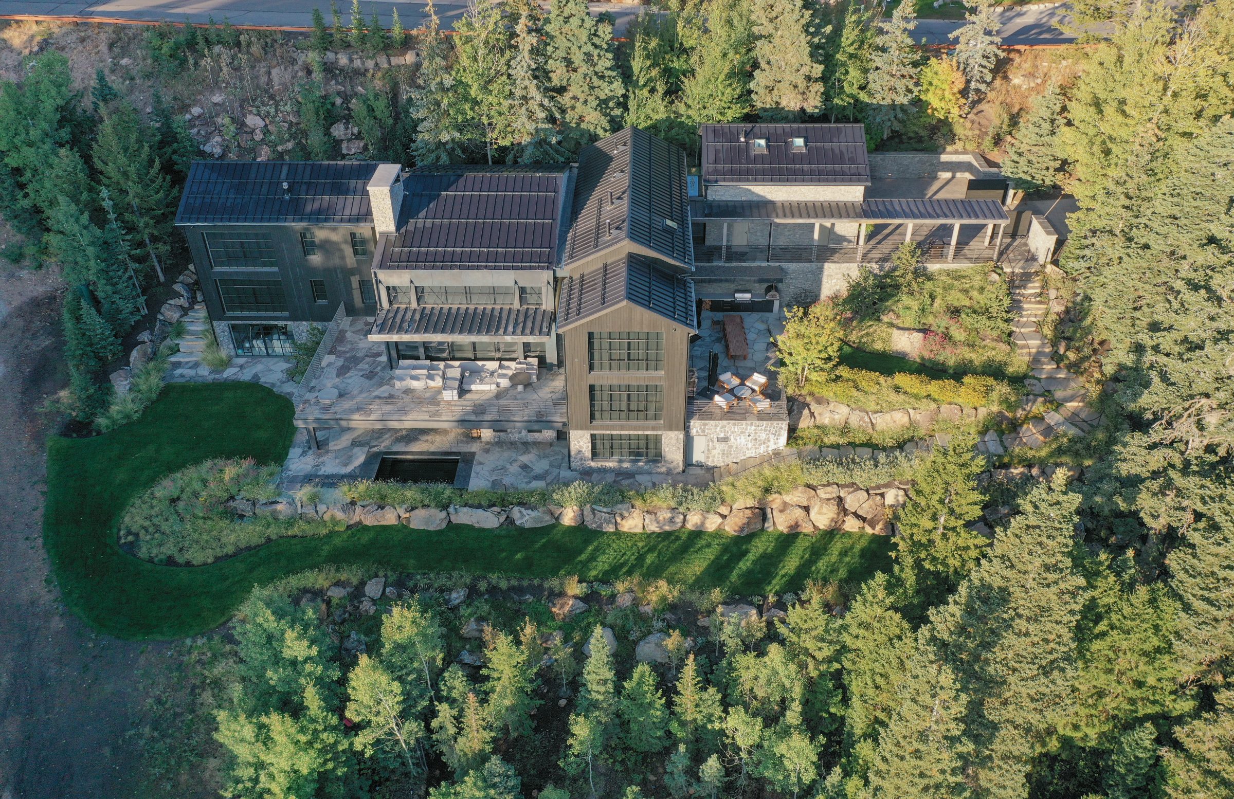 Aerial view of modern hillside home surrounded by trees.