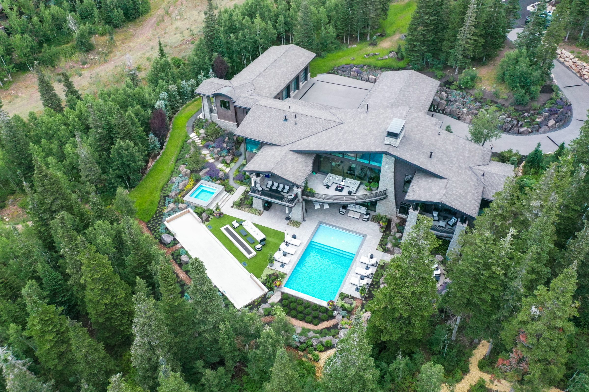 Aerial view of luxury house with pools and greenery.