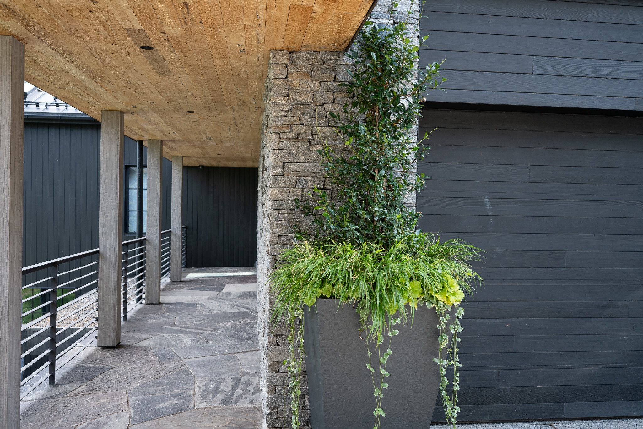 Modern exterior with potted plants and stone wall.