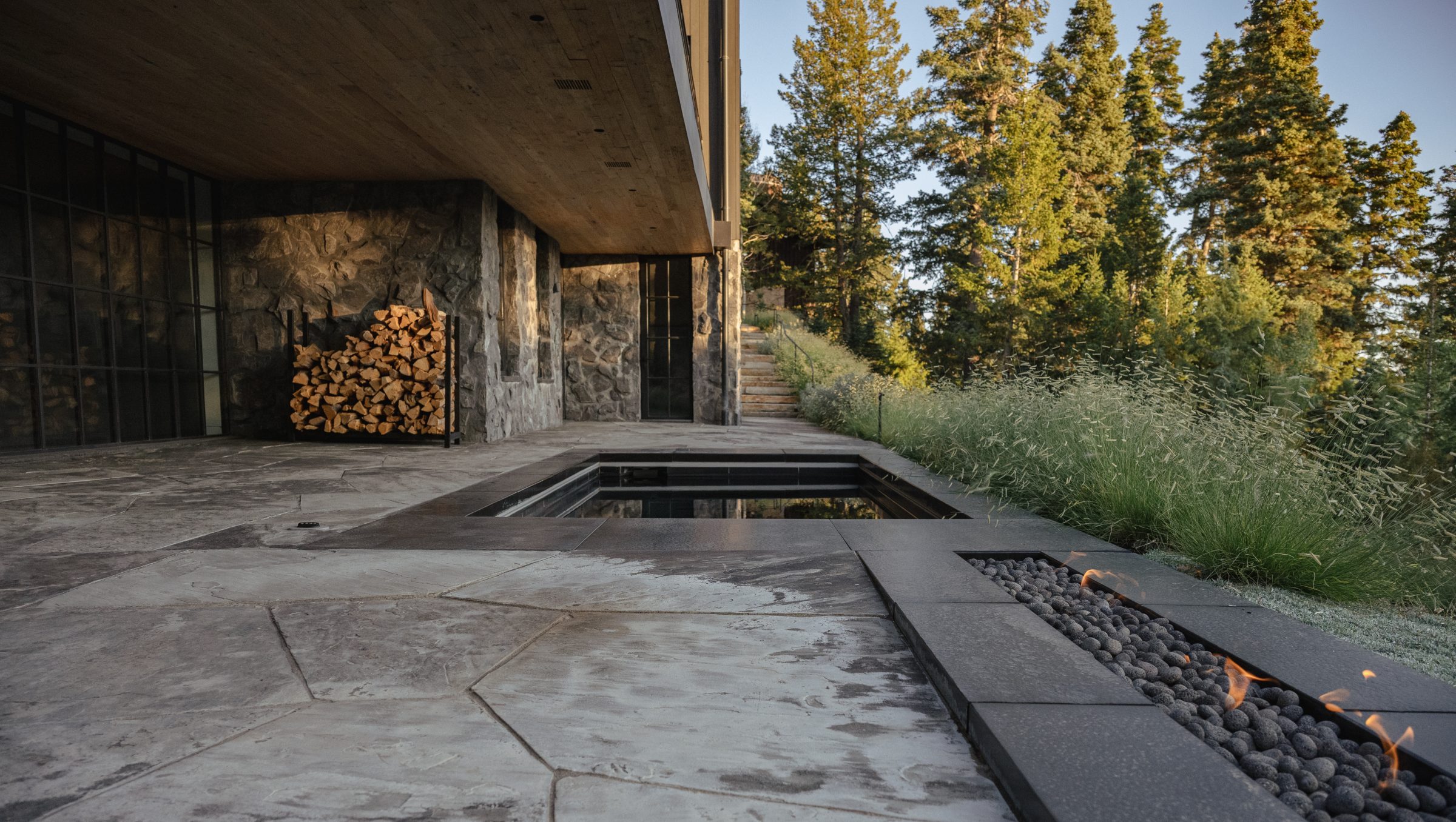 Modern patio with fire pit and woodpile.