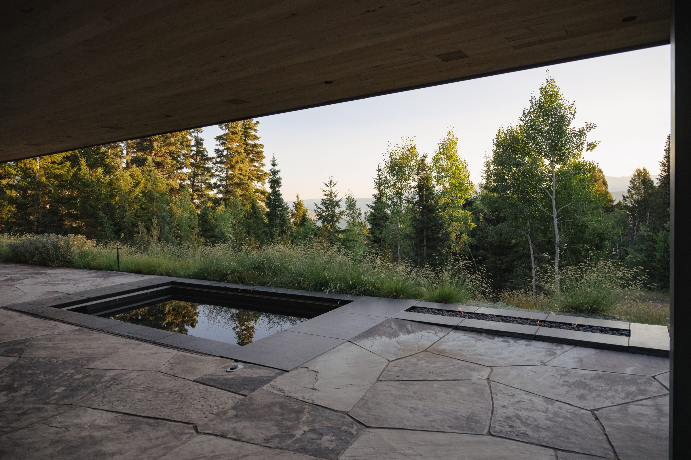 Modern patio with forest view and angular stones.